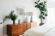 a mid-century modern stained dresser is used both for storage and for styling the space, it displays lamps and greenery