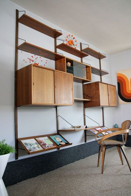 a mid-century modern wall unit with slated shelves in the lower part, two cabinets and symmetrical open shelves in the upper part