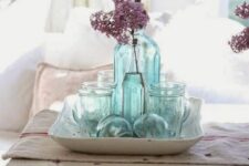 a pretty coastal centerpiece composed of a porcelain tray, light blue vintage bottles and jars and buoys is a cool idea and it’s easy to realize