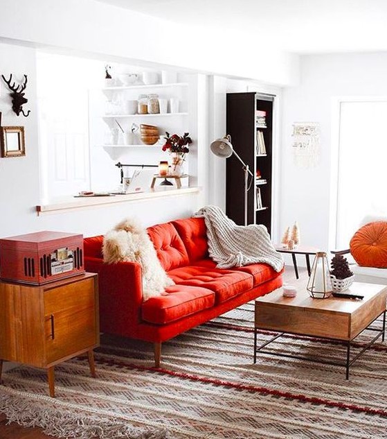A pretty mid century modern living room done in neutrals and spruced up with bold touches   a red sofa, a chest and an orange pillow