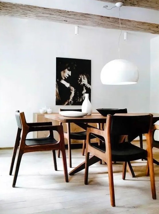 a refined yet simple mid-century modern dining space with a stained table and black chairs, a chic credenza and a bold artwork