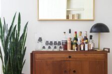 a rich-stained mid-century modern cabinet on casters as a home bar is a stylish idea for a mid-century modern space