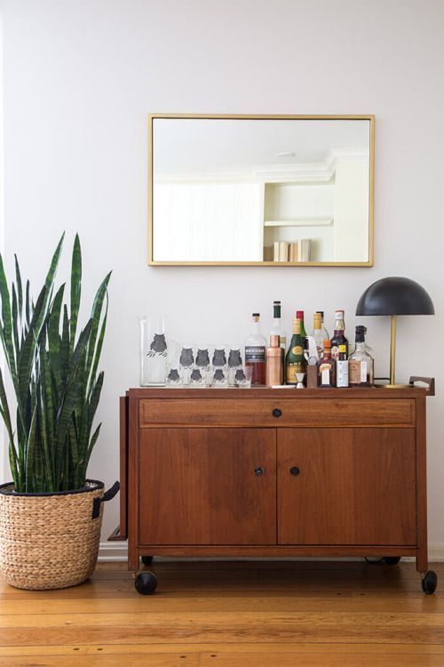 A rich stained mid century modern cabinet on casters as a home bar is a stylish idea for a mid century modern space