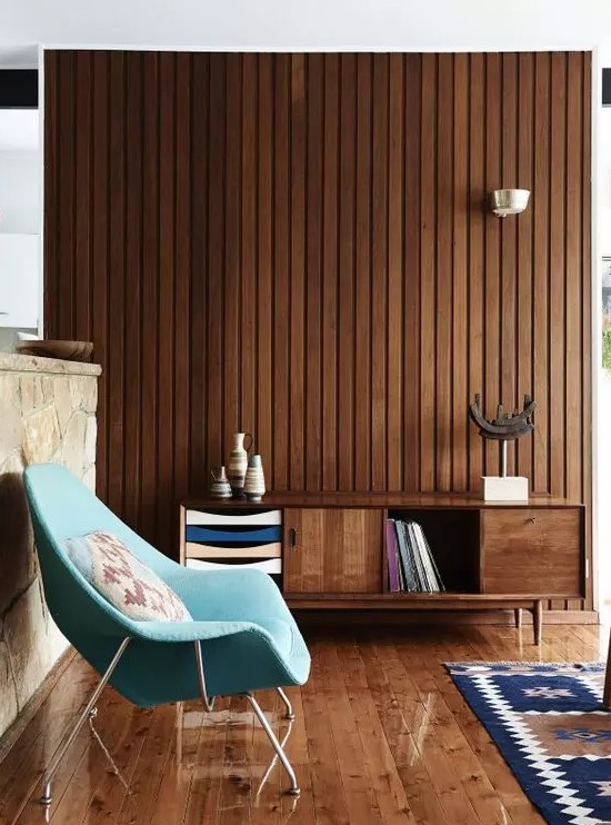 A rich stained mid century modern sideboard with doors, colorful drawers and an open storage compartment that matches the stained wall