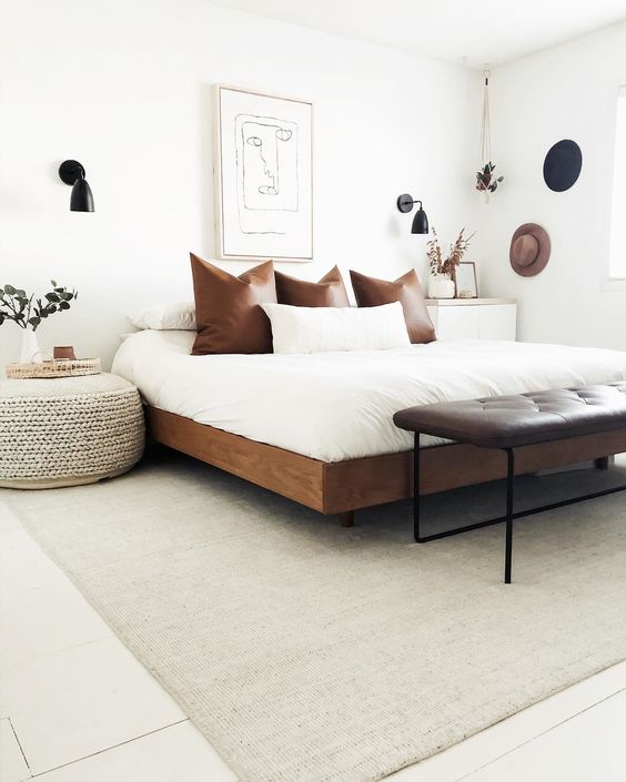 a rich-stained wooden bed, a leather bench and a woven ottoman for a mid-century boho bedroom
