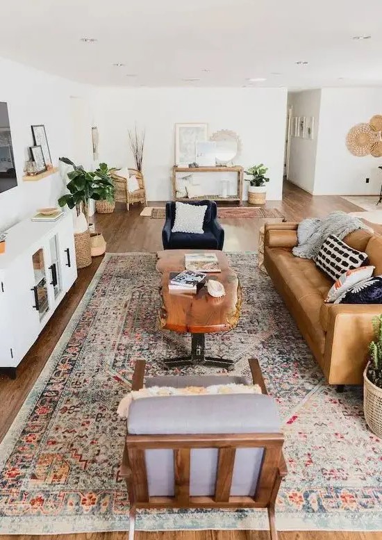 A stylish mid century modern farmhouse living room with a leather sofa, elegant chairs, a living edge table, potted plants