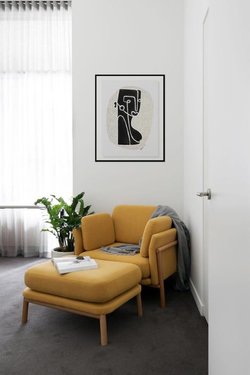 A yellow mid century modern chair with a matching footrest and pillows plus a grey blanket is a perfect idea for a reading nook
