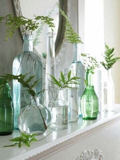 an arrangement of blue, neutral and green bottles with greenery is a cool idea for styling your mantel, windowsill or coffee table