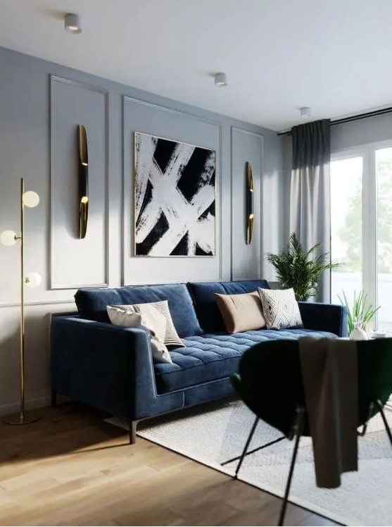 an elegant living room with dove grey walls, a modern navy sofa, a black chair, a chic artwork and some gold and brass touches for a chic look