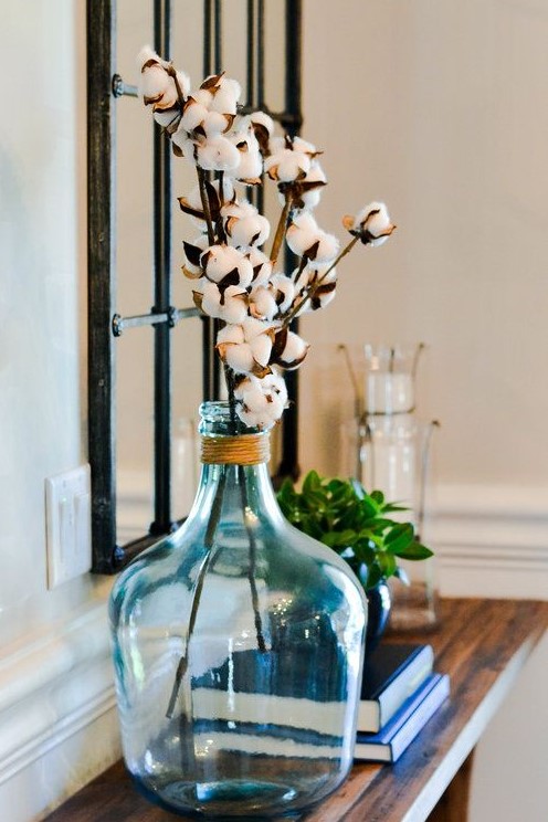 An oversized blue bottle with twine and cotton branches is a cute farmhouse inspired decoration to rock