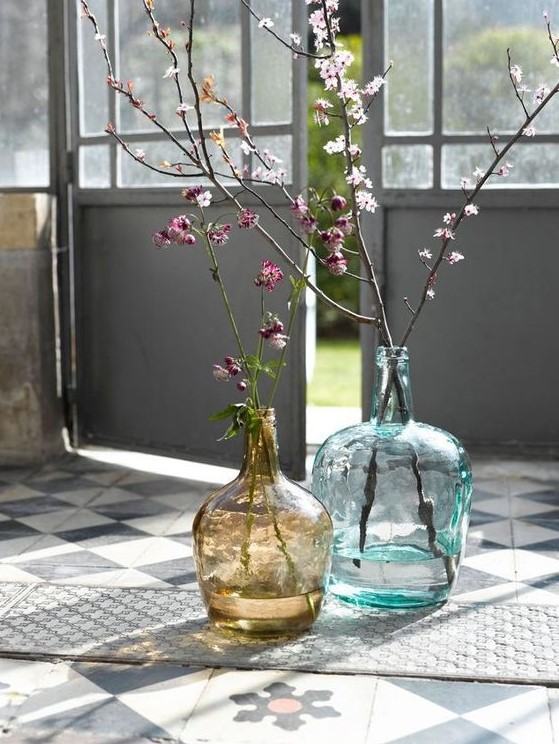 Large bottles in blue and brown with blooming branches make the space fresh, bright and spring filled