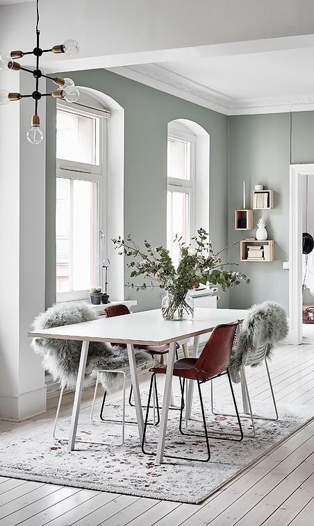 a Nordic dining zone with a sleek table and leather chairs covered with faux fur plus a printed rug
