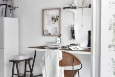 a Nordic neutral home office with a trestle desk, some wall-mounted shelves, a black stool and a woven rug