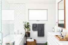 a Scandinavian bathroom with white and grey tiles, a basket for storage and potted plants
