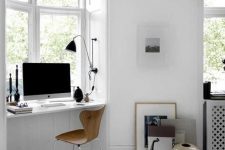 a Scandinavian white workspace with a windowsill desk, a wooden chair, some dramatic touches of black and art