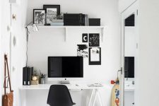 a black and white Scandinavian home office with a white trestle desk, a black chair, a white shelf and black decor, a glass pendant lamp