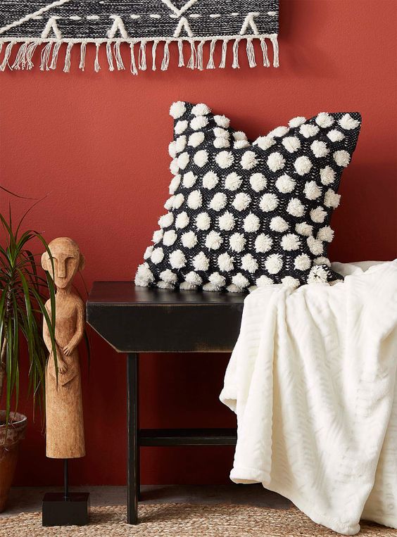 a black pillow with white pompoms for detailing is very contrasting and chic