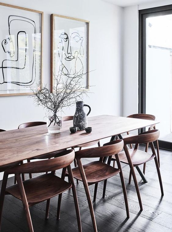 a catchy modern Scandi dining space with a stained table, stained rounded chairs and a mini gallery wall and vases