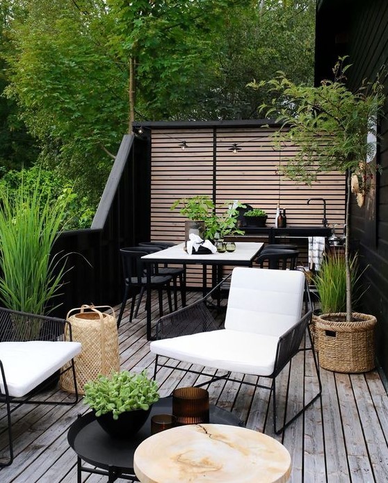 a chic and lively Scandinavian summer terrace with black and white furniture, a small kitchen countertop with a sink, a dining and sitting space