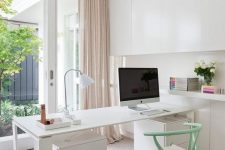 a chic neutral Scandi-inspired home office with a white storage unit that takes the whole wall, a desk and a mint chair