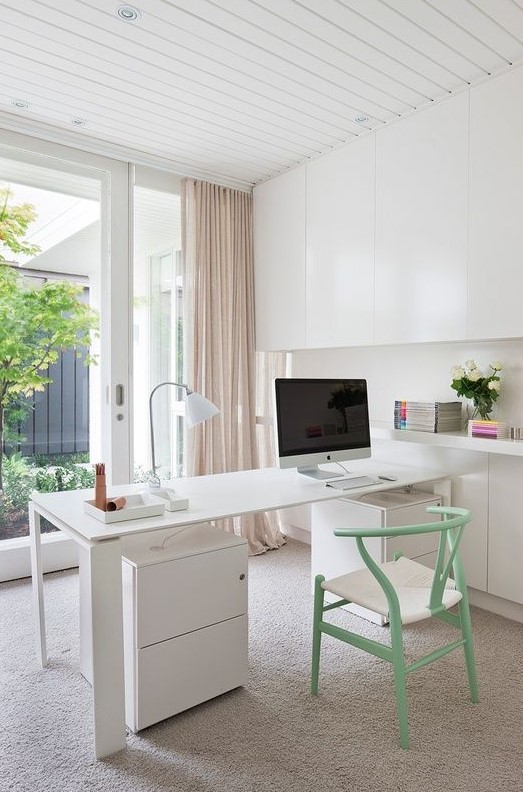 A chic neutral Scandi inspired home office with a white storage unit that takes the whole wall, a desk and a mint chair