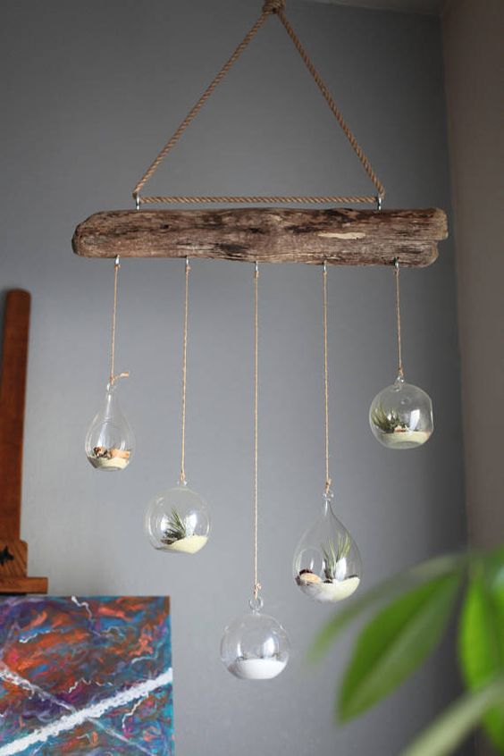 a dirftwood mobile with hanging glass bubbles with sand and air plants is a stylish beahcy piece