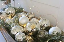 a dough bowl with mercury glass ornaments, fir branches and LED lights is a beautiful Christmas decoration