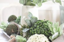 a dough bowl with moss and boxwood balls, fake blooms and greenery in a vase is a pretty rustic centerpiece
