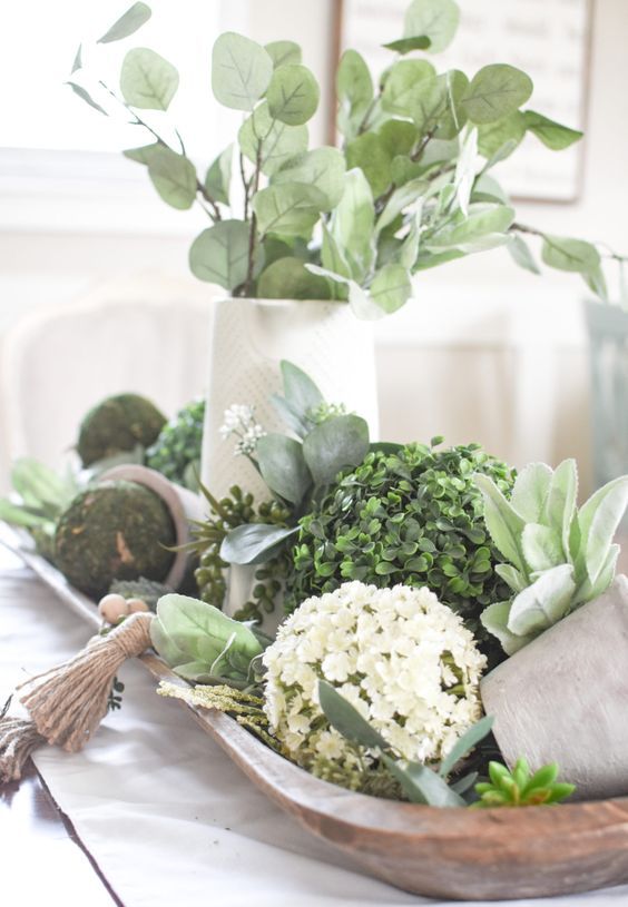 a dough bowl with moss and boxwood balls, fake blooms and greenery in a vase is a pretty rustic centerpiece