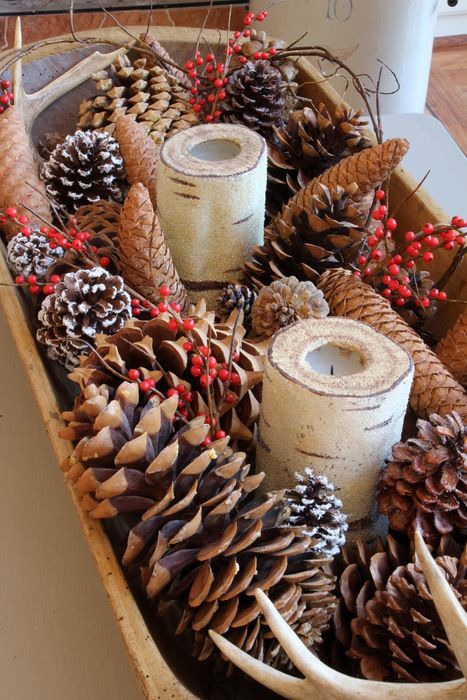 a dough bowl with pinecones of various sizes, with fake berries and birch branch candle holders