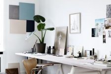 a dreamy Scandinavian home office with a large whitewashed desk, a plywood chair, a gallery wall and an artwork on the wall
