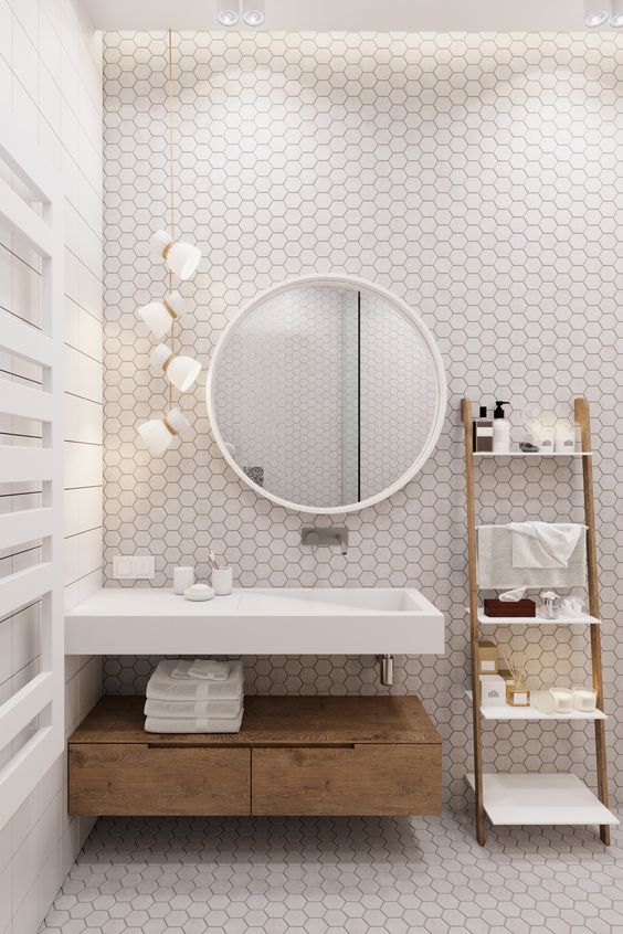 a fresh bathroom with white hex tiles and black grout, with light-colored wood and pendant lamps
