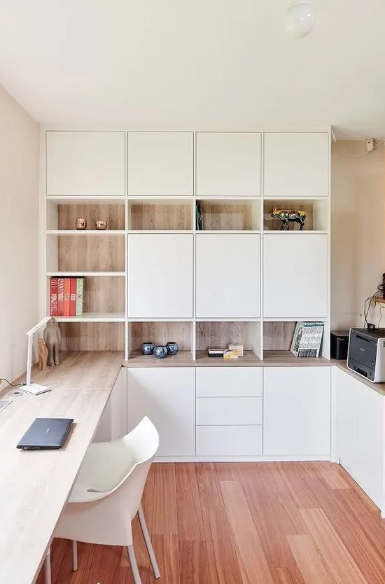 A functional Scandinavinhome office with white and stained storage units, with a built in desk and some pretty decor is very chic