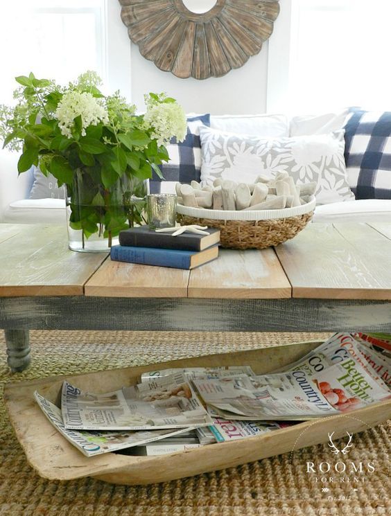 a large antique dough bowl is used to store magazines and newspapers under the coffee table