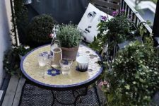 a monochromatic balcony with chairs and a lot of potted greenery is spruced up with a colorful mosaic table