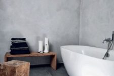 a natural Scandinavian bathroom done with concrete and grey tiles plus wooden stools and a bench