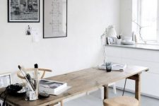a neutral Scandinavian home office with a wooden desk, wooden and cork stools, a pendant lamp and some black and white art