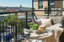 a neutral balcony with metal furniture, neutral textiles, potted greenery and lots of pillows is very welcoming