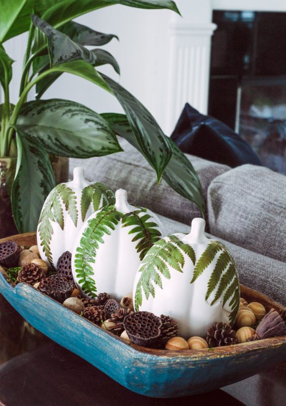a painted blue dough bowl with nuts, painted pumpkins with fern leaves, lotus and pinecones