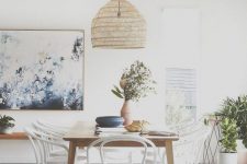 a pretty Scandinavian dining room with a sleek table, white and stain matching chairs, a woven pendant lamp and potted plants