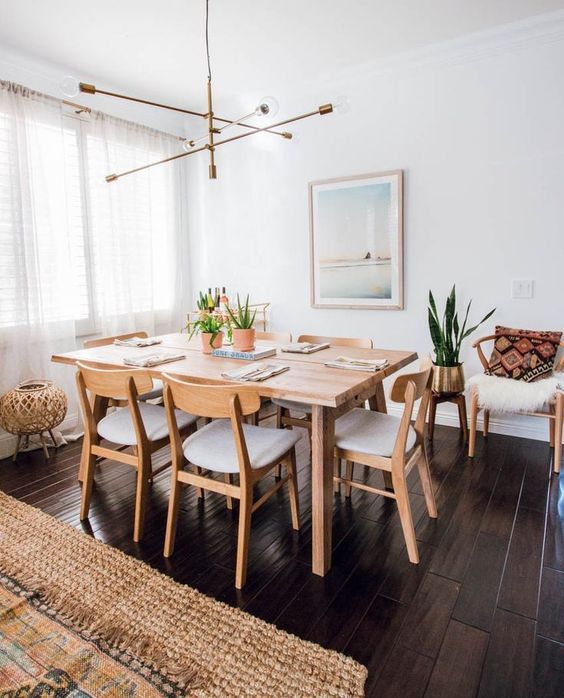 a pretty modern Scandinavian dining space with a stained table and neutral chairs, a dreamy artwork, a cool chandelier and faux fur