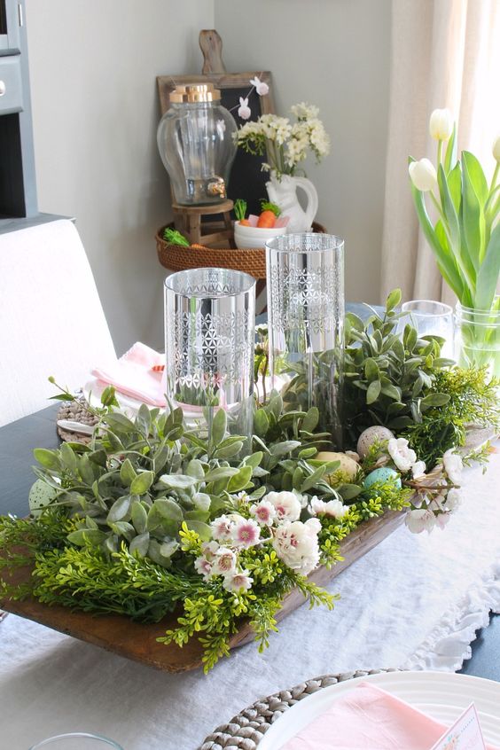 a refreshing spring centerpiece with a dough bowl, lush greenery, blush and neutrla blooms, fake eggs and candles