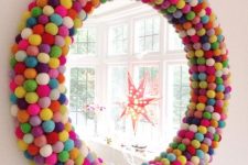 a round mirror covered with colorful pompoms to make it brighter and cooler is a bold accessory