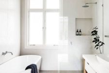 a serene Nordic bathroom with an oval tub, storage niches, a long vanity with a sink and potted greenery