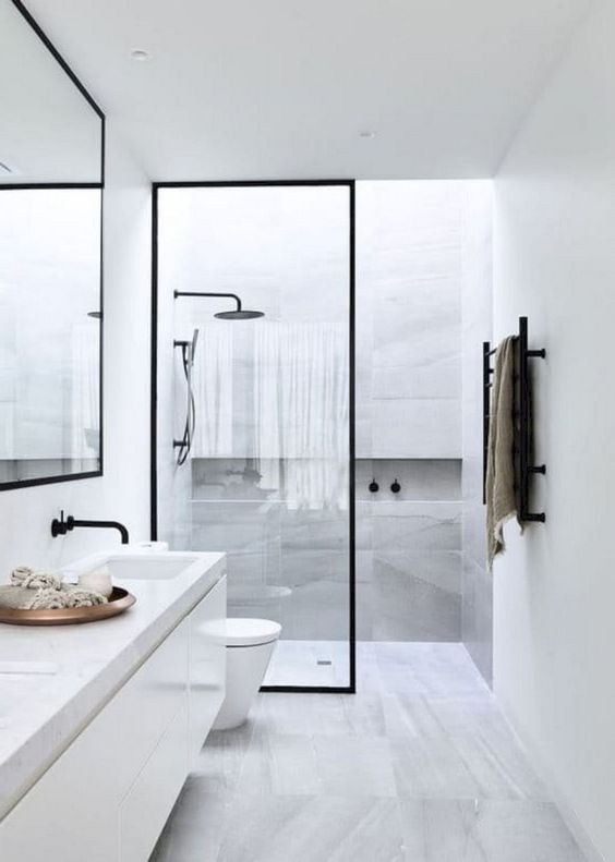 a serene Nordic bathroom with grey marble tiles, a long vanity and touches of black