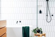 a serene Scandinavian bathroom with speckled floor, white tiles with black grout and wooden furniture
