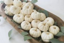 a simple and elegant fall centerpiece of a dough bowl filled with white pumpkins and some greenery