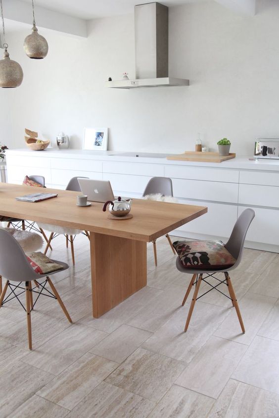 A sleek Nordic dining room with a light stained table and matching grey chairs plus metal pendant lamps
