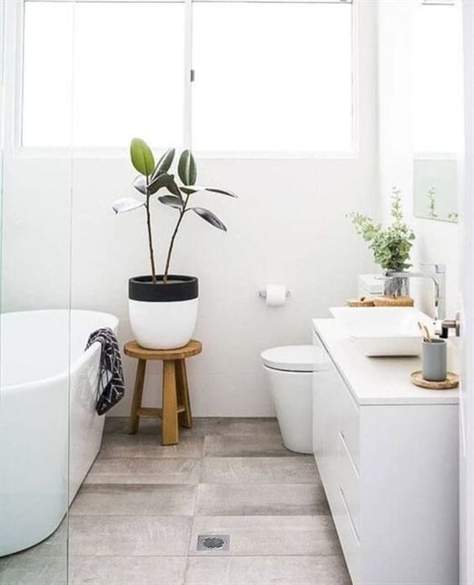 a small Nordic bathroom with a wood tiile floor, a white vanity, an oval tub and potted greenery