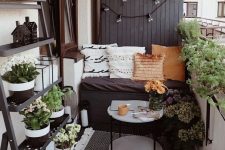 a tiny monochromatic balcony with black and white walls, blakc furniture, potted greenery and blooms and various pillows and rugs